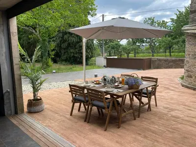 a wooden table with an umbrella on a patio at A Casa do Souto, Santiago de Compostela in Sigüeiro
