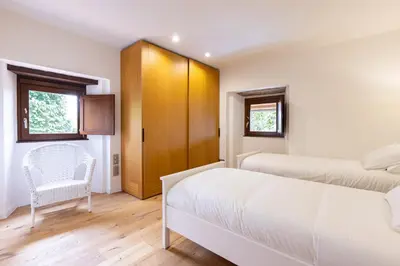 a bedroom with two beds and a chair at A Casa do Souto, Santiago de Compostela in Sigüeiro