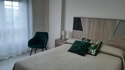 a bedroom with a bed and a green chair at Vial Sol in Viveiro