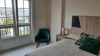 a bedroom with a bed and a chair and a window at Vial Sol in Viveiro