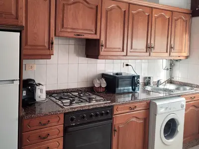 a kitchen with wooden cabinets and a stove top oven at PIso de 3 habitaciones en centro de Miño in Miño