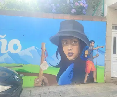 a mural on the side of a building with a woman with a hat at PIso de 3 habitaciones en centro de Miño in Miño