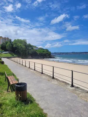 a bench next to a beach with a trash can at PIso de 3 habitaciones en centro de Miño in Miño