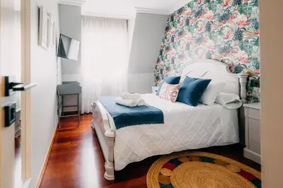a bedroom with a bed with a floral accent wall at PENSIÓN CALDEA in Caldas de Reis