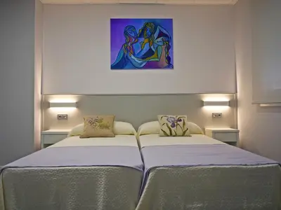 two beds in a room with a painting on the wall at Siaba Pensión Boutique in Sigüeiro