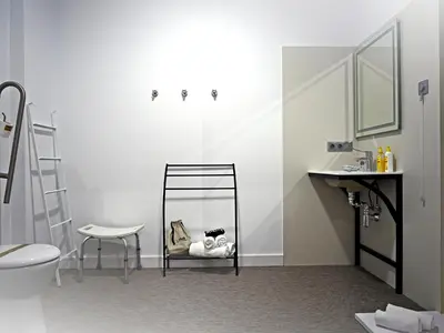 a bathroom with a toilet and a chair and a sink at Siaba Pensión Boutique in Sigüeiro