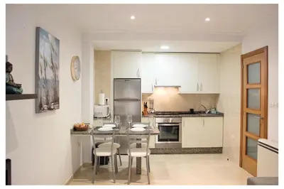 a kitchen with white cabinets and a table and chairs at Apartamento TIERRA in Viveiro