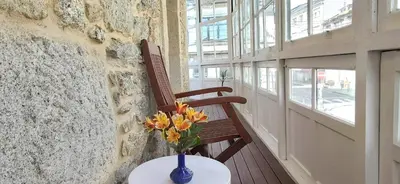 a vase of flowers sitting on a table next to a chair at APARTAMENTO CÉNTRICO, AMPLIO y LUMINOSO in Guitiriz