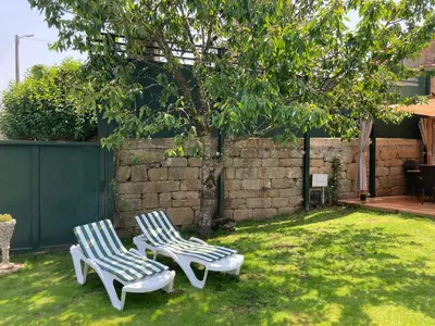 two lawn chairs sitting in a yard with a tree at A casa da Ita in Ourense