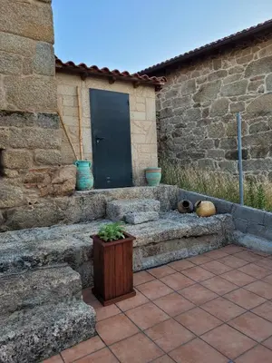 a stone patio with a black door and a bench at A casa da Ita in Ourense
