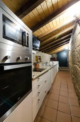 a kitchen with white cabinets and a black oven at A casa da Ita in Ourense