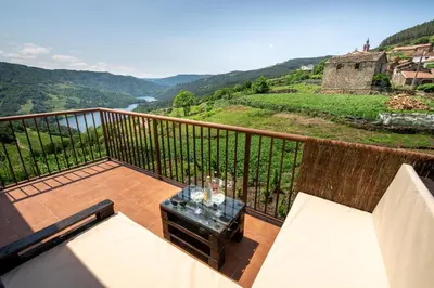 a balcony with a table with wine glasses on it at Casa Visita Ribeira Sacra in Chantada