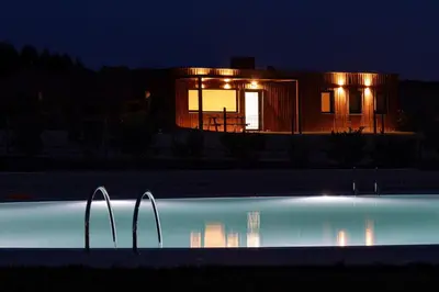 a house lit up at night with a swimming pool at Beche EcoCamp in Santa Eulalia
