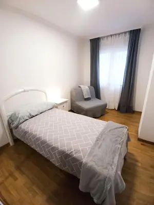a bedroom with a bed and a chair and a window at Viveiro Muralla in Viveiro