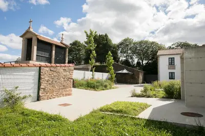 a driveway leading to a house with a stone wall at ALBERGUE O FERVELLO in Santiago de Compostela