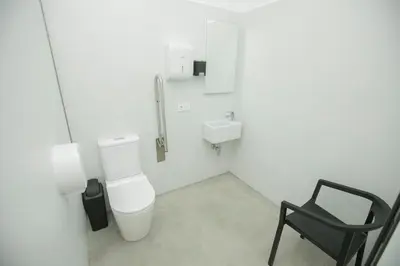 a bathroom with a toilet and a sink and a chair at ALBERGUE O FERVELLO in Santiago de Compostela