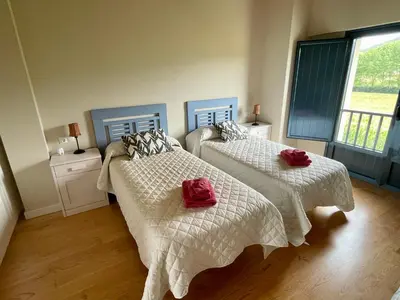 a bedroom with two beds with white and red sheets at Grandes Duplex nuevos con Jardin y Barbacoa - 3 llaves, Los Gayoles Rural in Castropol