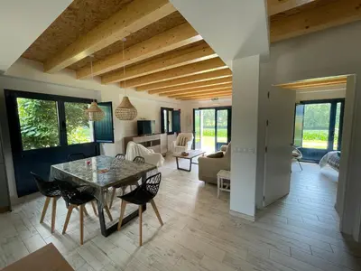 a dining room and living room with a table and chairs at Grandes Duplex nuevos con Jardin y Barbacoa - 3 llaves, Los Gayoles Rural in Castropol