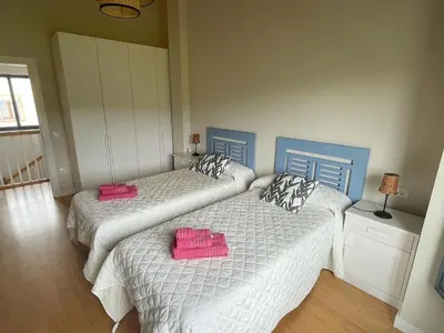 two beds in a bedroom with pink towels on them at Grandes Duplex nuevos con Jardin y Barbacoa - 3 llaves, Los Gayoles Rural in Castropol