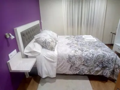 a bedroom with a bed and a chair and purple walls at Casa o Cantón in Berredo
