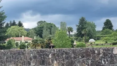 a stone wall in front of a house at Finca Bouzas in Teo