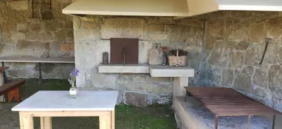 a stone wall with a table and a bench at Finca Bouzas in Teo
