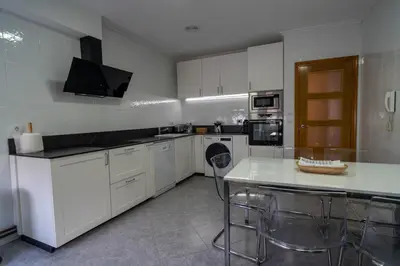 a kitchen with white cabinets and a table and chairs at APARTAMENTOS SARMIENTO in Mondoñedo