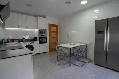 a kitchen with a table and a refrigerator at APARTAMENTOS SARMIENTO in Mondoñedo