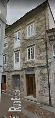 an old stone building with white windows on a street at APARTAMENTOS SARMIENTO in Mondoñedo