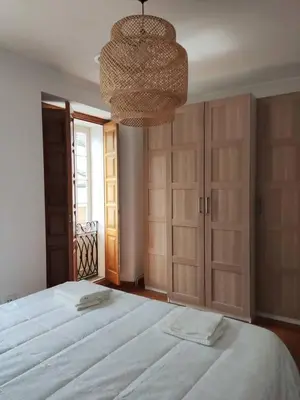 a bedroom with a large white bed and a chandelier at APARTAMENTOS SARMIENTO in Mondoñedo