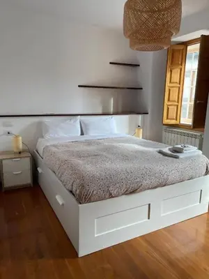 a white bed in a bedroom with a wooden floor at APARTAMENTOS SARMIENTO in Mondoñedo