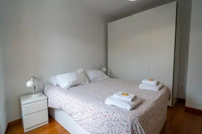 a white bedroom with two towels on a bed at APARTAMENTOS SARMIENTO in Mondoñedo