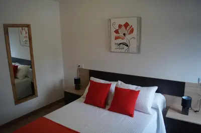a bedroom with a bed with red pillows and a mirror at Casa Marisa in Teo