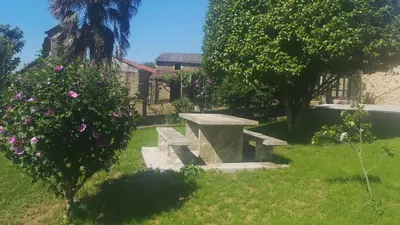 a stone bench in a yard with flowers at Casa Marisa in Teo