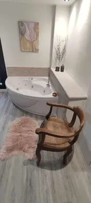 a bathroom with a bath tub and a wooden chair at Precioso Apartamento 1 Hab con Bañera Hidromasaje in O Barco de Valdeorras