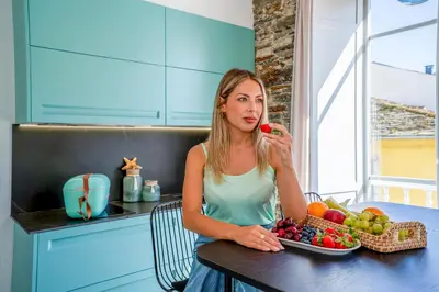 a woman sitting at a table with a bowl of fruit at Apartamentos Turísticos Casa Arango in Ribadeo