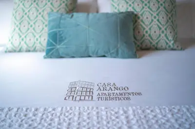 a bed with a pillow and a sign on it at Apartamentos Turísticos Casa Arango in Ribadeo