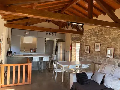 a living room with a couch and a table and a kitchen at Casa Rural Elvira Ribeira Sacra in Asma