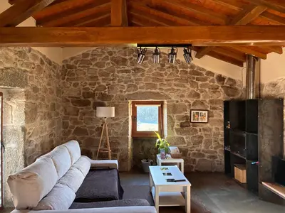 a living room with a couch and a stone wall at Casa Rural Elvira Ribeira Sacra in Asma