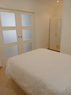a bedroom with a white bed and two windows at Apartamentos Tras dos Fornos in Chantada