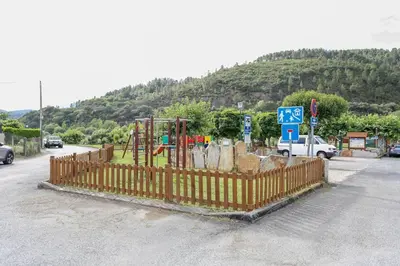 a playground with a fence next to a road at Villa Albino Piscina climatizada in Ribas del Sil