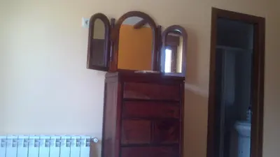 a wooden dresser with two mirrors on a wall at Casa Rustica CESAR in Lubián