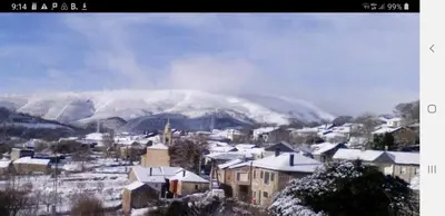 a small town with snow covered buildings and a mountain at Casa Rustica CESAR in Lubián