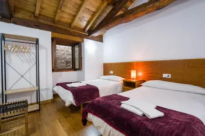 two beds in a room with wooden ceilings at Casa D'Abaixo in Arzúa