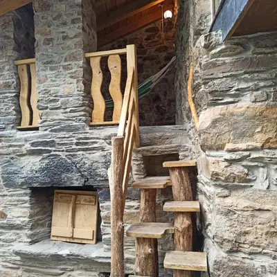 a set of stairs in a cabin with a stone wall at Casa do Bico in Becerreá