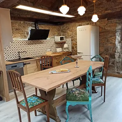 a kitchen with a wooden table and chairs at Casa do Bico in Becerreá