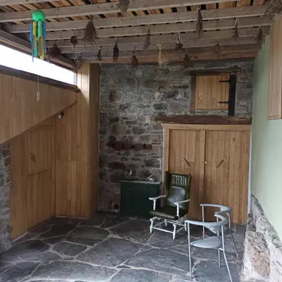 a room with two chairs and a stone wall at Casa do Bico in Becerreá