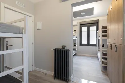 a room with a hallway with bunk beds and a radiator at Albergue Alda Pilgrim Ponferrada in Ponferrada