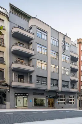 a tall gray building with windows on a street at Albergue Alda Pilgrim Ponferrada in Ponferrada