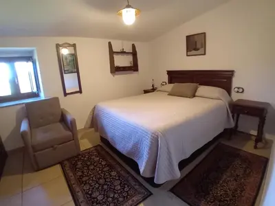 a bedroom with a bed and a chair at Stone Cottage La COMPOSTELANA in Curtis